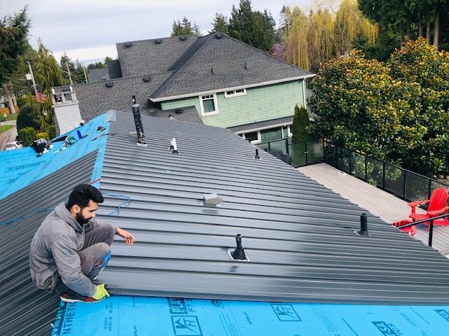 Metal panel roof being installed over blue underlay